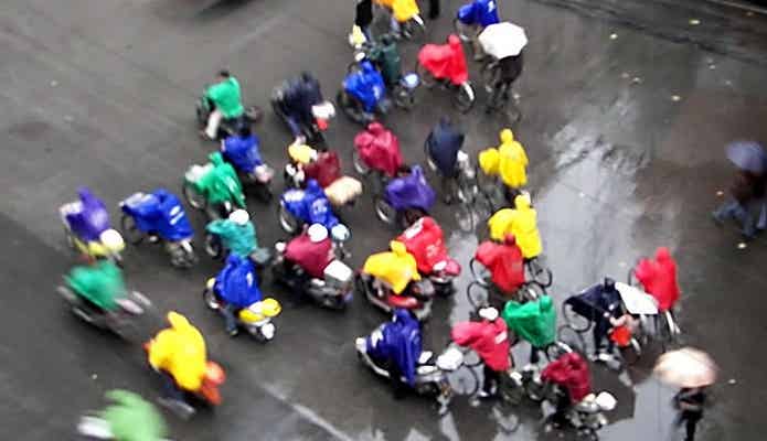 明るい色のレインコートで自転車に乗る人びと