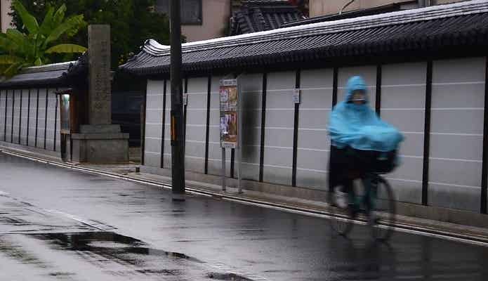 ポンチョタイプのレインコートで自転車に乗る人