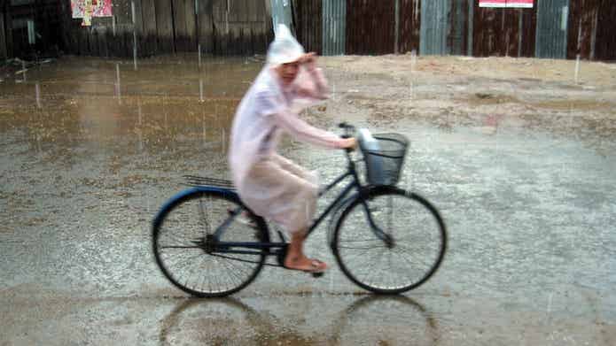 レインコートを着て自転車を漕ぐ女性