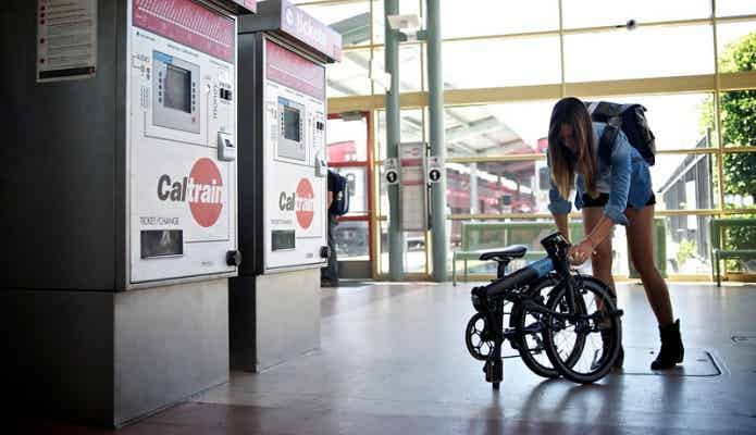 駅で折りたたみ自転車を組み立てる女性