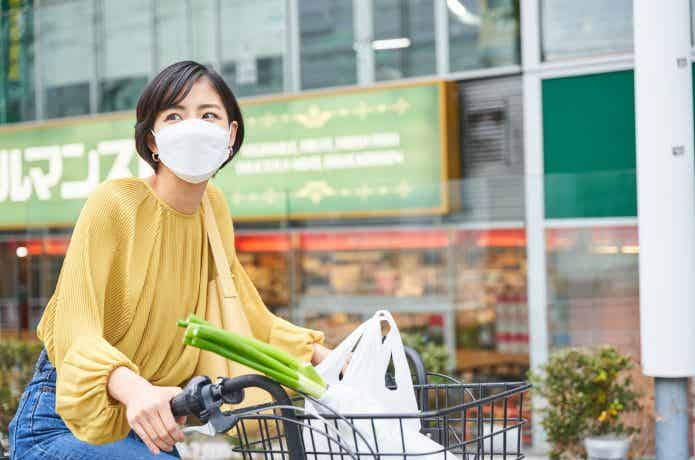 自転車のカゴに買い物袋を入れた女性
