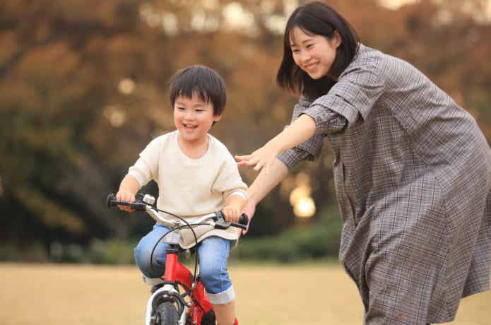 自転車の練習をする子どもと親