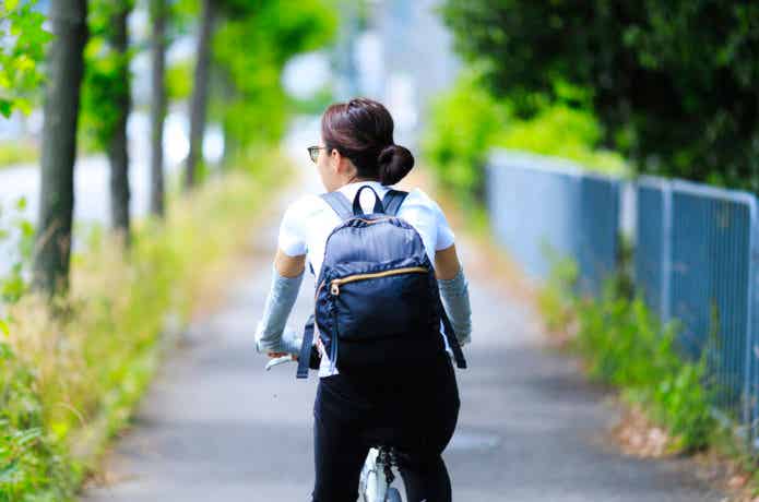 リュックを背負って自転車で走る女性