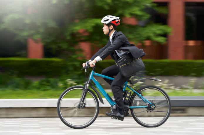 スーツにヘルメットで自転車通勤する男性