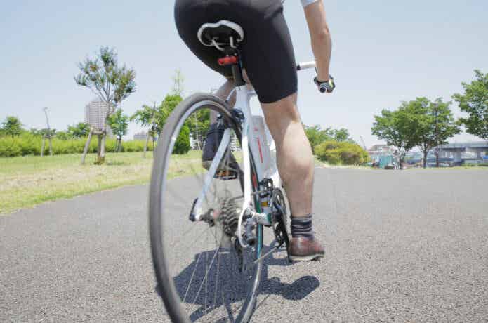 足を伸ばした状態でロードバイクに乗る男性