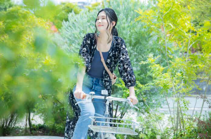 カゴ付きクロスバイクでサイクリングする女性