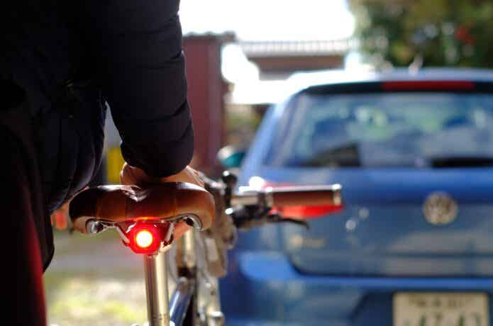 テールライトがついた自転車を運ぶ男性