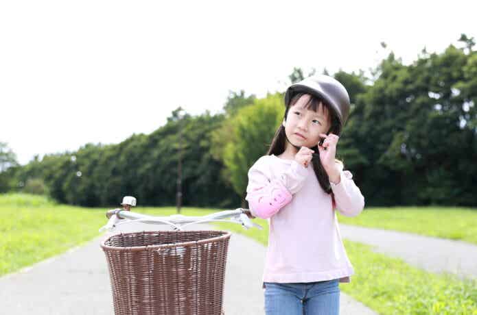 自転車から降りて、ヘルメットを取ろうとする少女