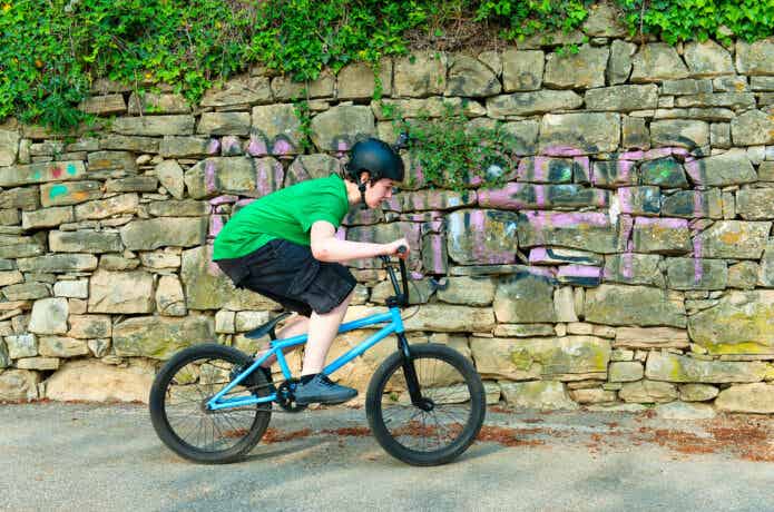 ストリートでヘルメットをかぶってBMXで走る少年