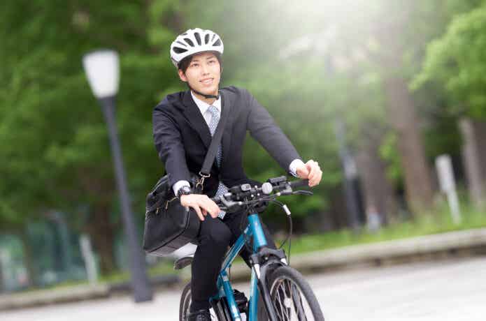 ヘルメットをかぶってクロスバイクに乗るビジネスマン