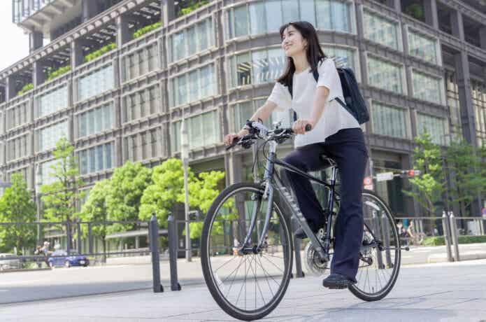 都会をクロスバイクに乗って走る女性