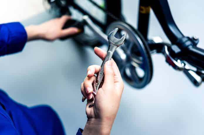 レンチを持って自転車をメンテナンスする人