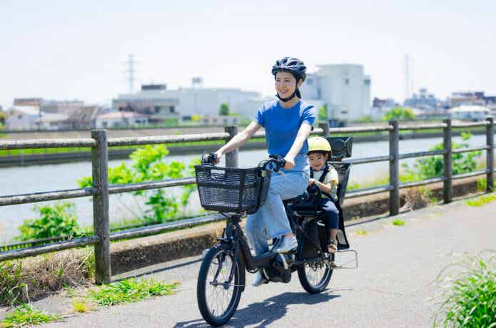 電動自転車に子供を乗せて走る女性