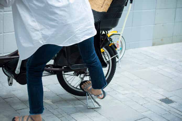 電動自転車のスタンドを立てる女性