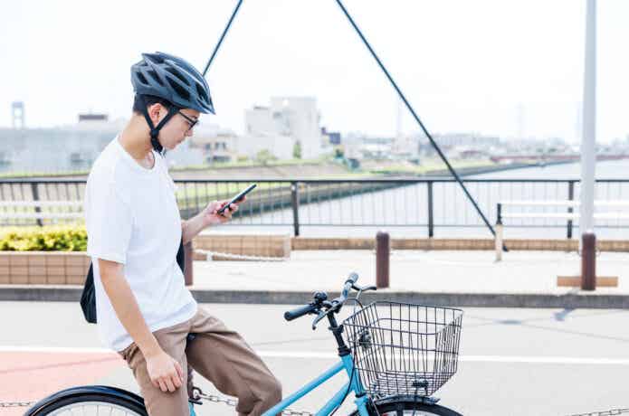 自転車を止めて、スマホを見る男性