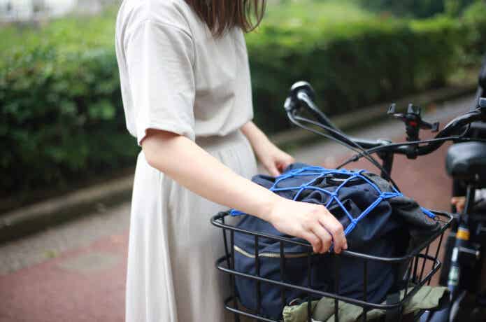 自転車の前かごにカバンを積む女性