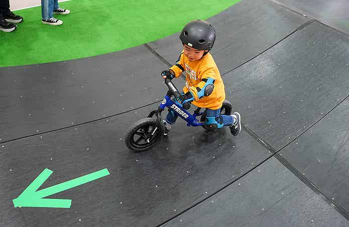 キッズ・フィールドをキックバイクで楽しむ子ども