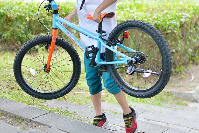 階段でヨツバサイクル持ち上げている子ども