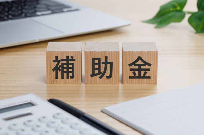 補助金と書いた積み木とPC