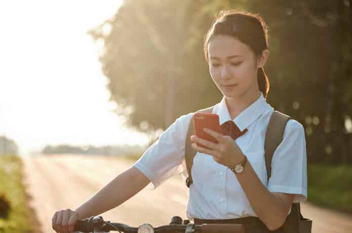 自転車を止め、スマホを見る女子高生