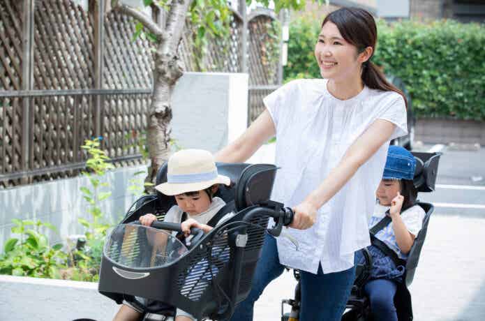 2人の子供を乗せ、自転車で出発する女性