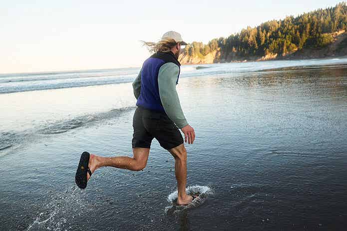 海辺をサンダルで走る男性