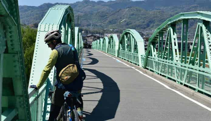 橋をわたるロードバイクに座る男性