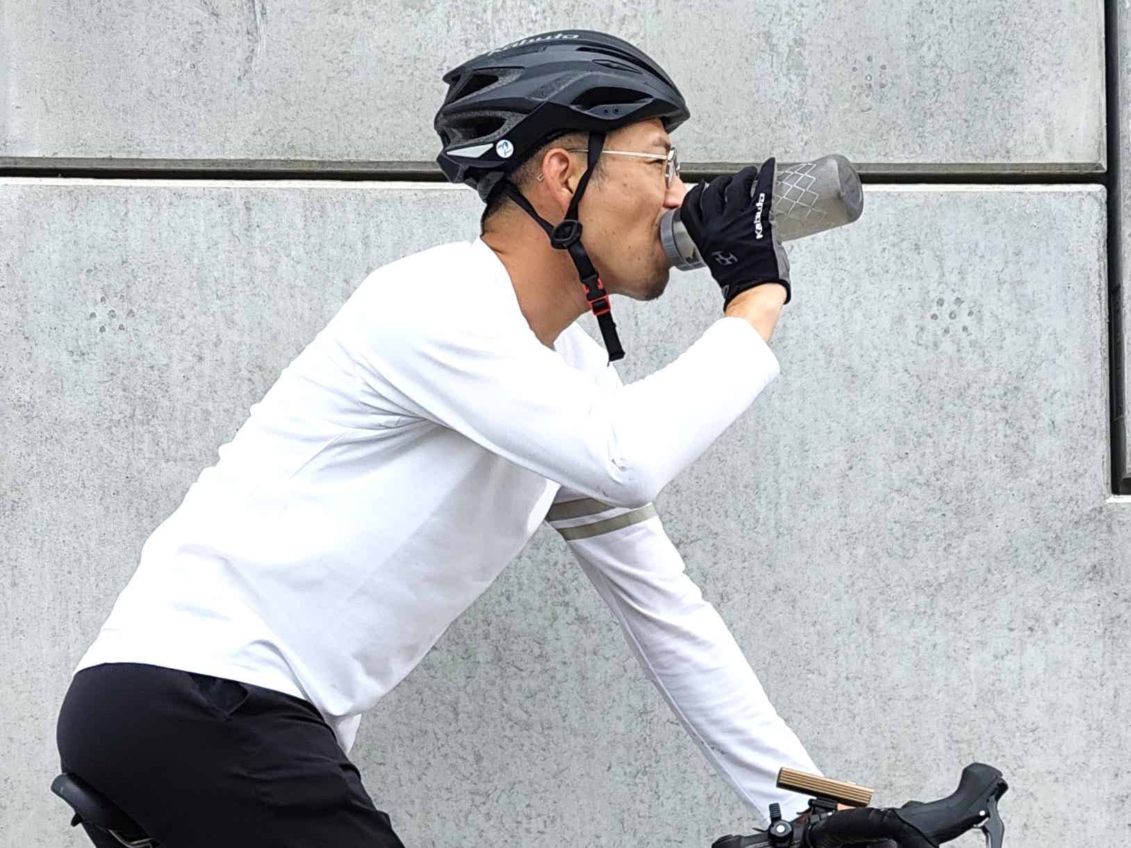 ロードバイクでボトルを傾けて飲む筆者