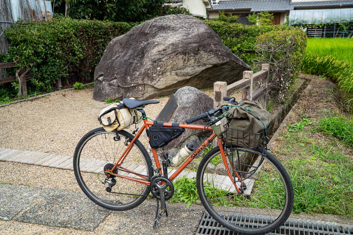 亀石のそばに停めたオレンジ色のツーリング自転車