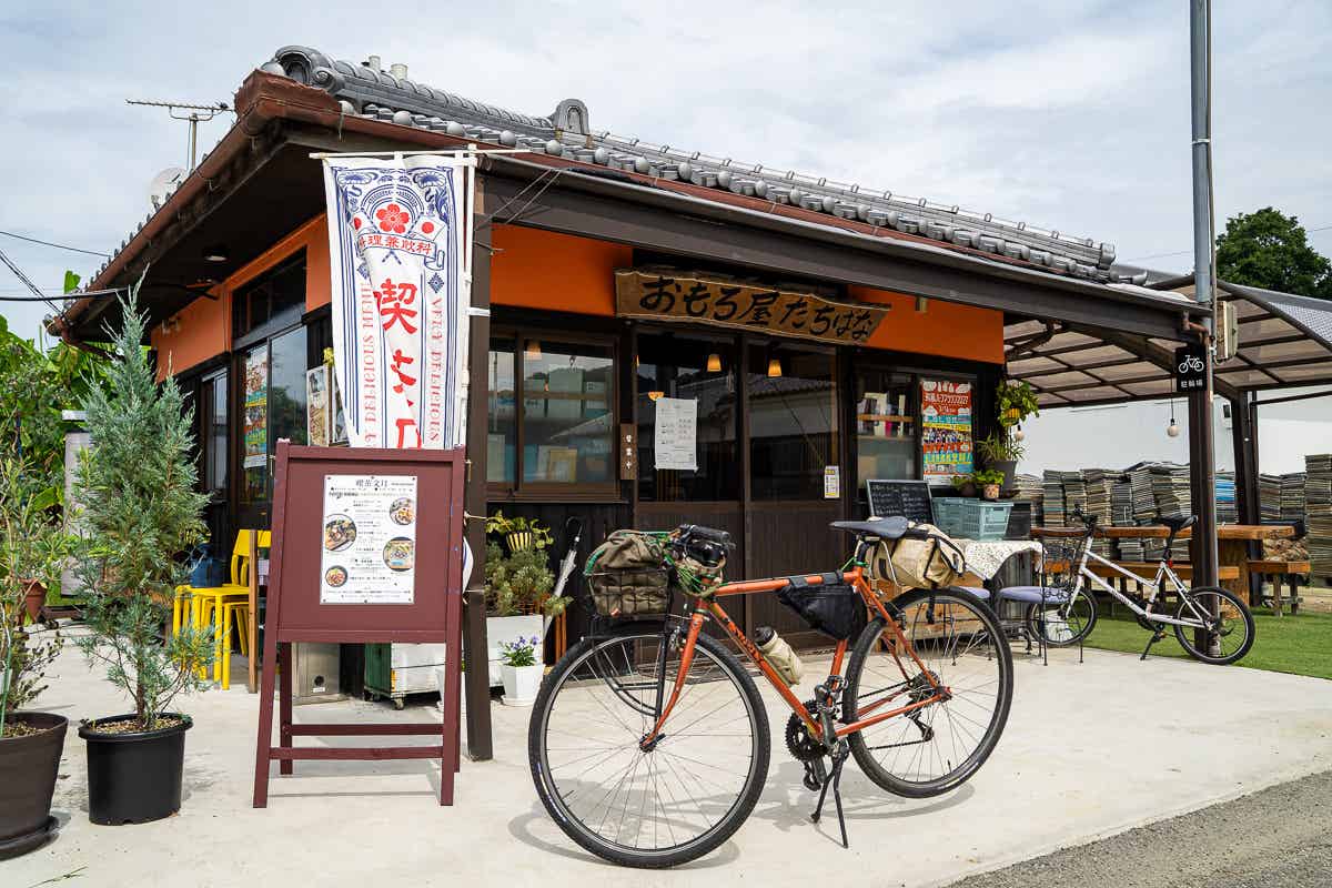 赤い看板と自転車が置かれた食事処の店先