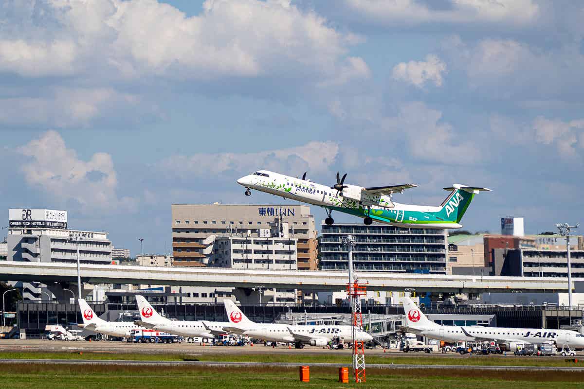 伊丹空港の滑走路から離陸する旅客機と駐機する機体